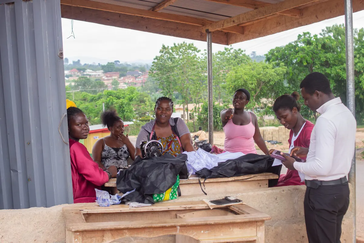 A field researcher recording responses on a handheld device while a tailoring group talks through their work
