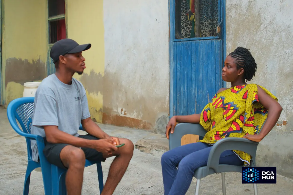 A researcher and a resident talking face to face, seated in a compound yard during a study visit
