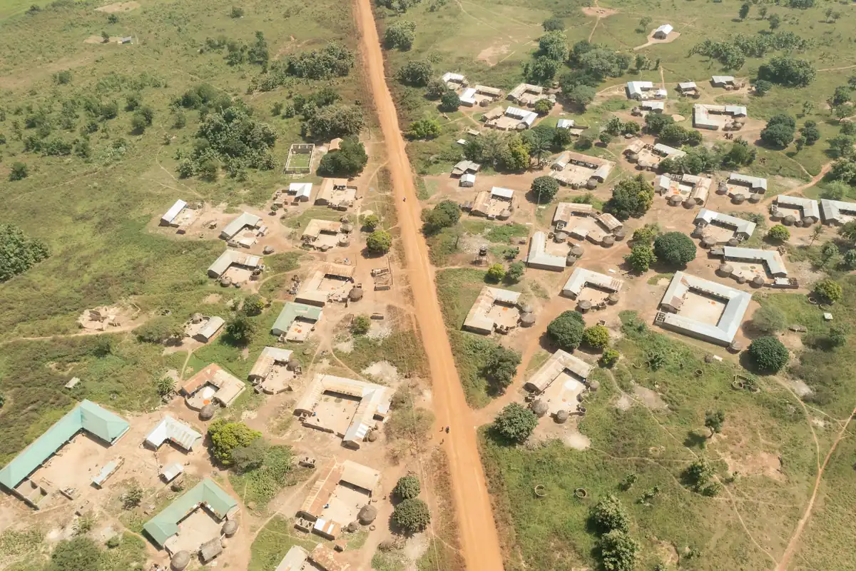 A rural village seen from the air, compounds spread either side of a single laterite road